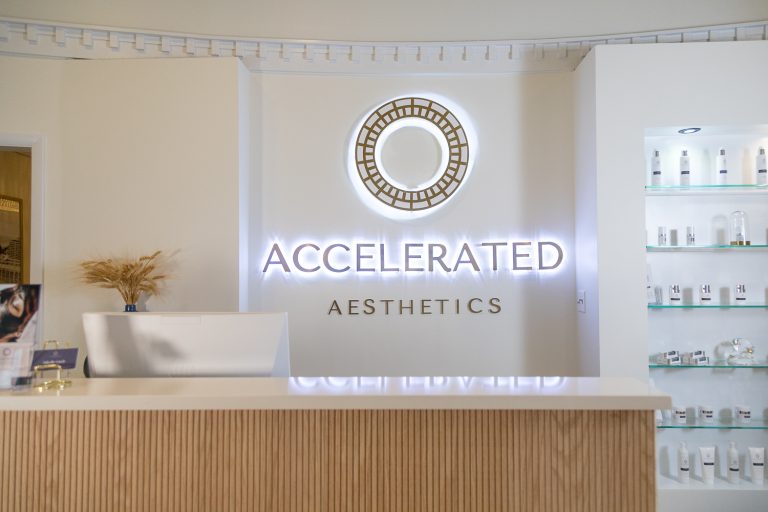 Reception area and illuminated logo at Accelerated Aesthetics medspa in downtown Elmhurst, IL